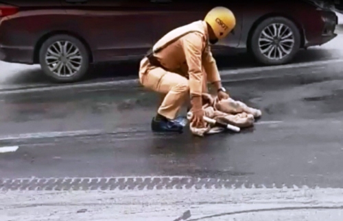 Chiến sĩ CSGT dùng giẻ cặm cụi lau vết dầu loang trên mặt đường