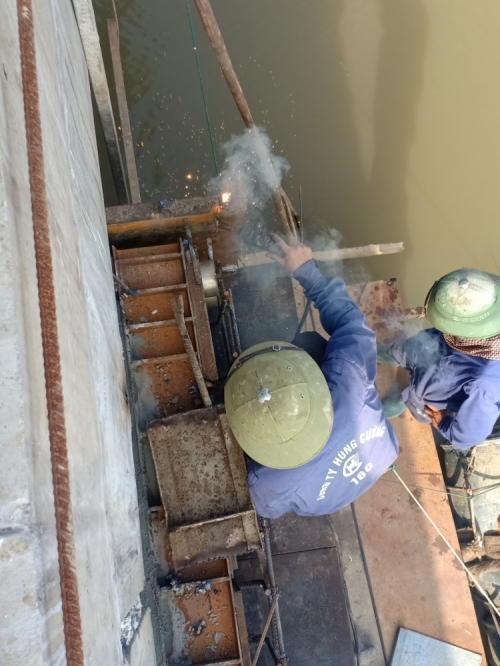 Đội công nhân thuộc nhà thầu Hùng Cường - Công ty CP Xây lắp và thương mại Hùng Cường đang tập trung hàn gắn lại hệ thống sắt thép bó ôm vào trụ cầu để chuẩn bị đổ bêtông gia cố thêm