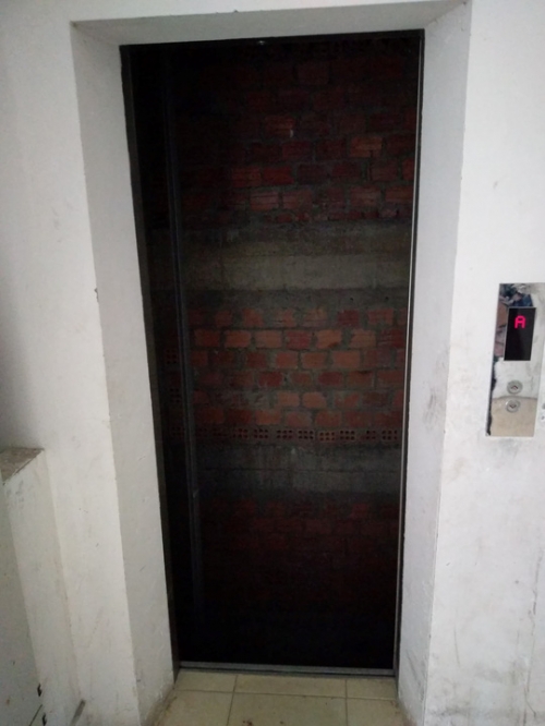 Sau lớp cửa mở, bên trong thang máy trống hoác, lộ cả bức tường gạch