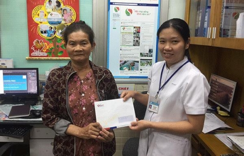 Mẹ em Tam nhận quà của bạn đọc Báo VietNamNet trao tặng.