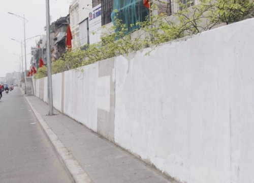 UBND phường Yên Phụ dùng sơn trắng để xoá bỏ những bức vẽ bẩn trên đoạn đê Nghi Tàm.